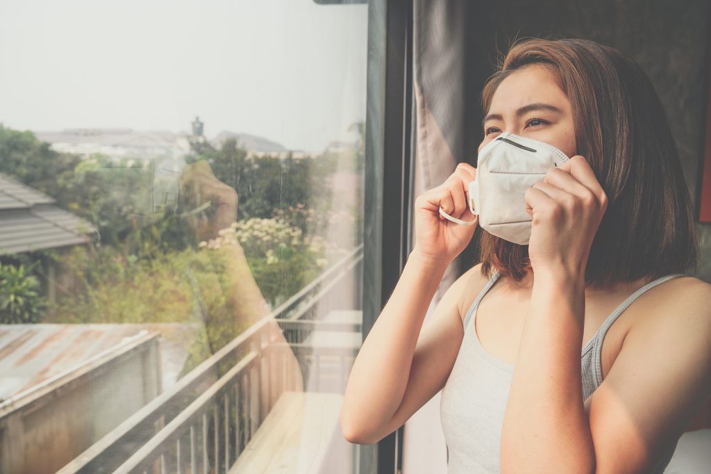 A woman wearing a mask due to breathing problems associated with poor indoor air quality