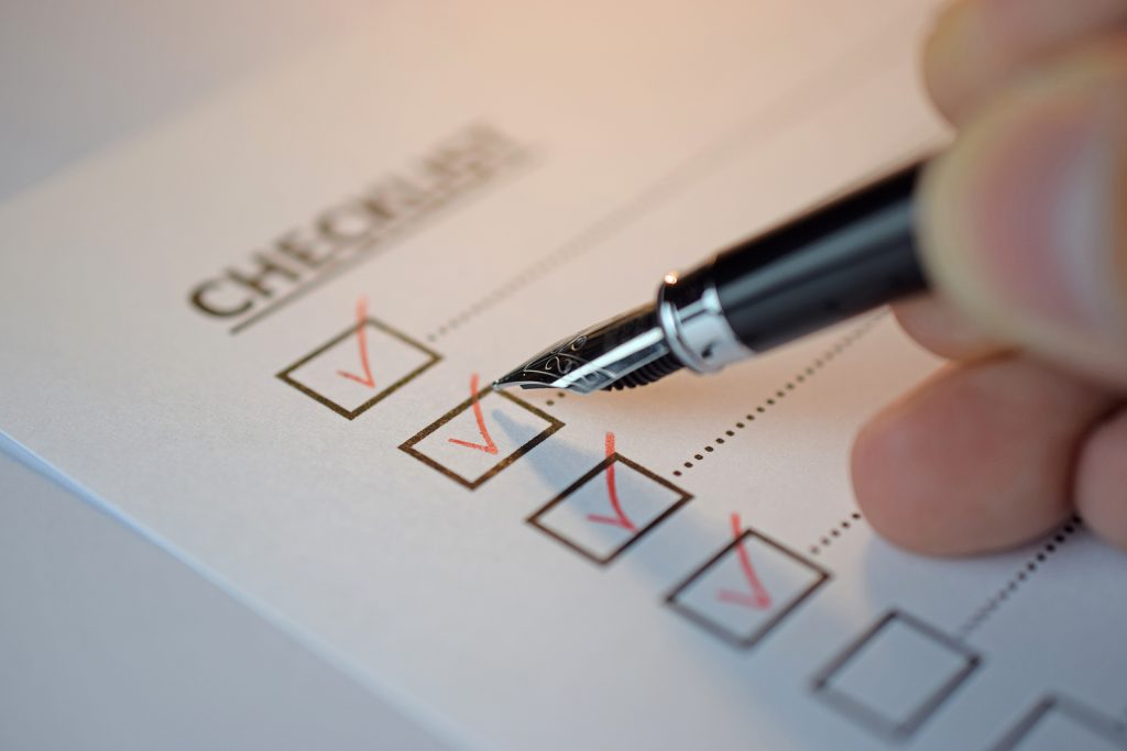 checklist box with red checkmark, paper and a pen with checklist word on table