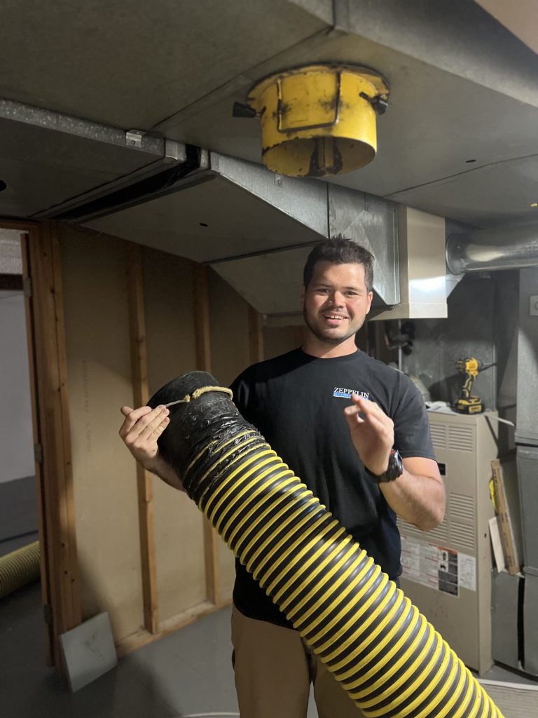 Man holding a hose used in an industrial & specialty air duct cleaning